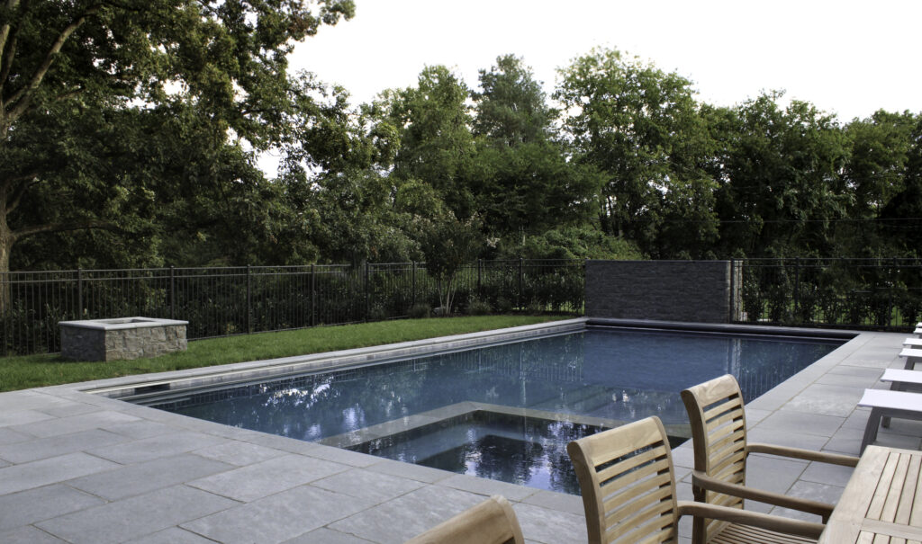 Oak-hill-2; backyard swimming pool with stone surrounding and patio chairs; pool builder in College Grove, TN; pool builder in Brentwood, TN; luxury pool; custom pools
